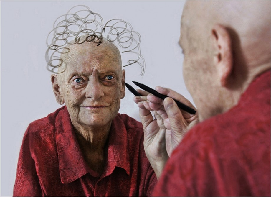 portrait of an old lady with cancer drawing hair on her reflection in the mirror